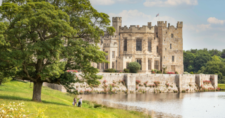 Family walking in the deer park at Raby Castle on a bright sunny day with Raby Castle in the background.